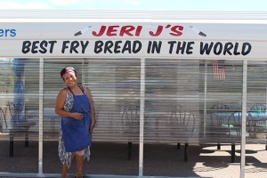 Jeri J herself poses next to the canopied dining area at her road side Indian Fry Bread stand.